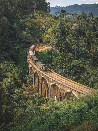 Un train d'époque traverse l'emblématique pont aux neuf arches du Sri Lanka, serpentant à travers des forêts et des collines verdoyantes. Ce chef-d'œuvre d'ingénierie, sur fond de végétation épaisse et de terrain montagneux, ajoute à la beauté du paysage, tout comme "Un billet pour le passé" (Sri Lanka) de Fine Art Shots.