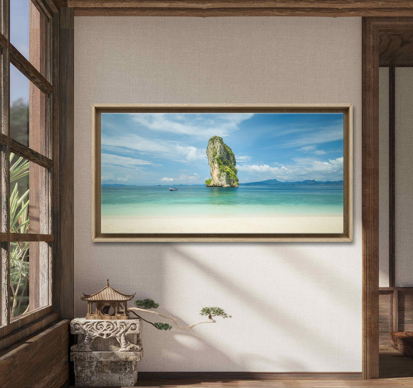 Une pièce sereine aux accents en bois présente une grande peinture de paysage marin encadrée sur le mur. Le tableau "Vue sur rocher" (Thaïlande) de Fine Art Shots représente une haute formation rocheuse dans des eaux turquoise sous un ciel bleu. Un bonsaï et une petite pagode décorative sont posés sur une table rustique sous le tableau.